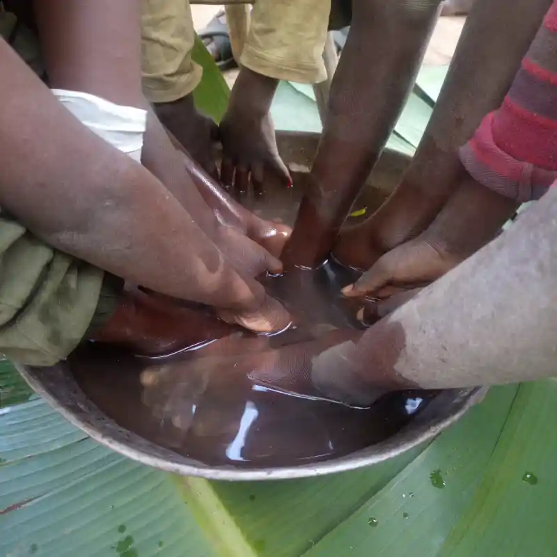 Children in Bungoma participating in an anti-jigger campaign with their feet being cleaned in a large metallic bowl before treatment, facilitated by DestinyImpact CBO