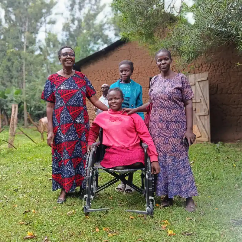 A DestinyImpact CBO beneficiary of the disability aid program poses with the organization’s chairperson and treasurer during a wheelchair and crutches donation event in Bungoma.