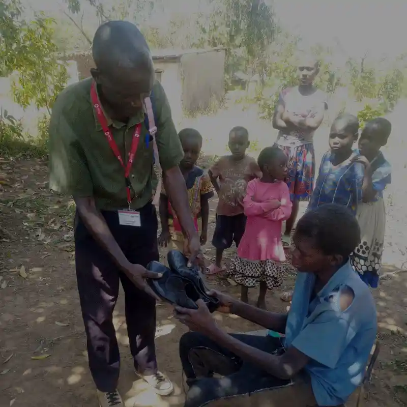 Close-up of a DestinyImpact CBO shoe donation in Bungoma, where a beneficiary of an anti-jigger campaign receives new footwear to protect against re-infestation and restore mobility.