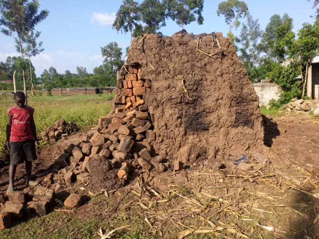 A young boy watches over a mound of freshly fired bricks, a symbol of community strength and Destiny Impact’s mission to build hope from the ground up.