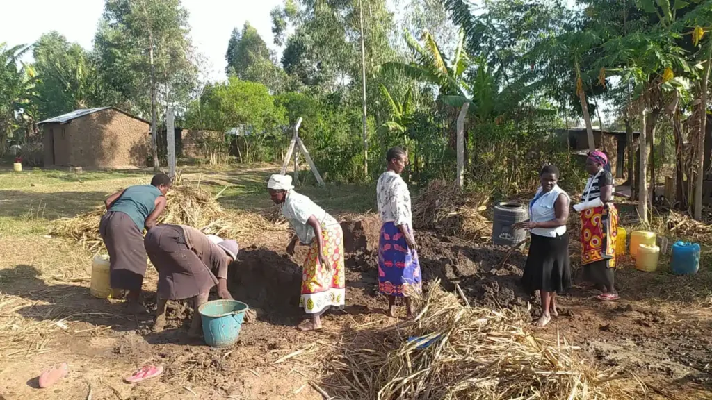 Women beneficiaries under Destiny Impact CBO preparing clay soil for brick making as part of an economic empowerment project in Bungoma County.