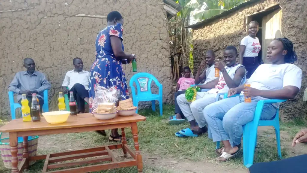 Michael standing with his family at home after passing his national examinations, joined by Destiny Impact staff.