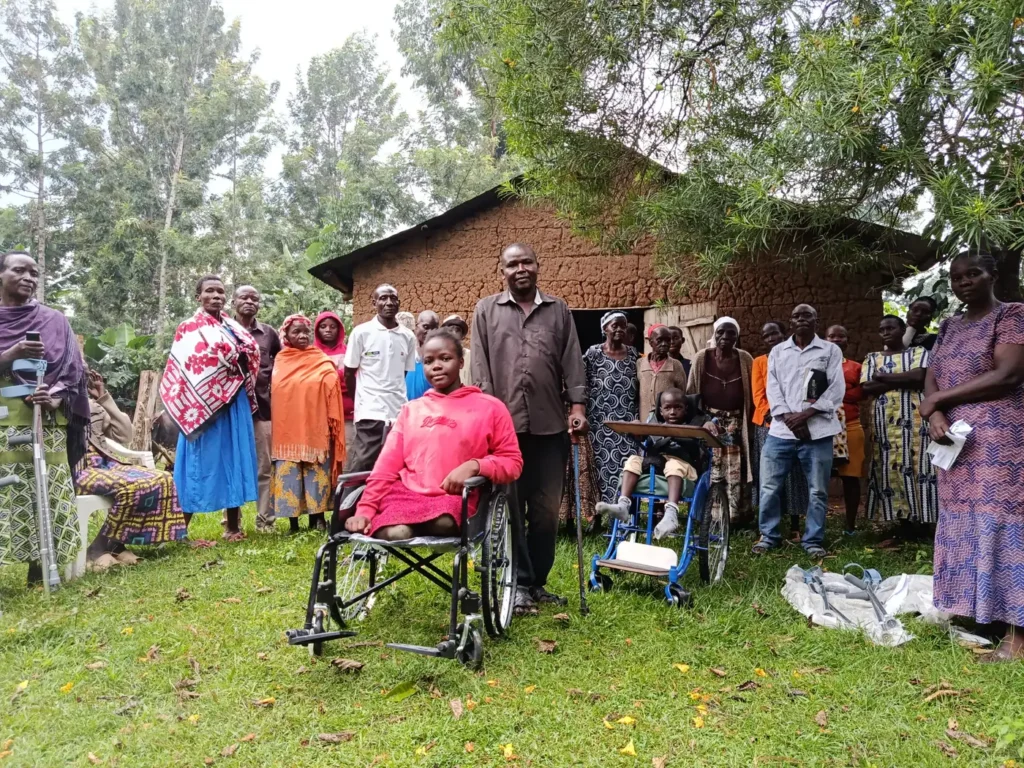 A young woman in a new wheelchair with members of the disability group. Mobility aids donated by NCPWD, handed over at Ng'oli, Bungoma County, 23 August 2025