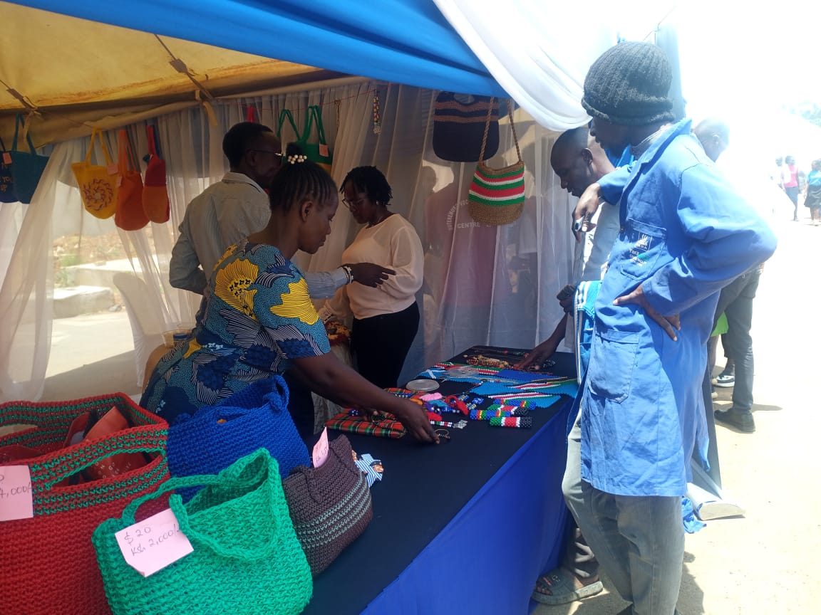 Women showing handmade bags and beadwork at an exhibition stall